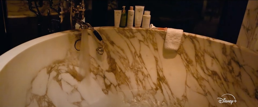 Bathtub with running water and toiletries along the rim.