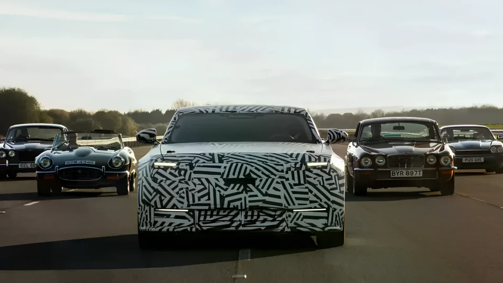 Камуфльований новий Jaguar на трасі в оточенні класичних автомобілів, вигляд спереду