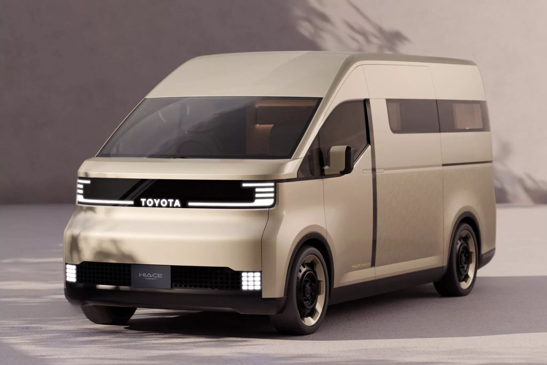 Beige futuristic Toyota van viewed from the front-right, with slim LED headlights and a TOYOTA grille label.