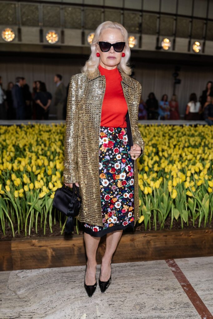 квітчаста спідниця, червоний гольф і золотисте пальто на дерев'яному столі
