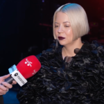 Свічка, складена вишиванка і дитяче черевичко на дерев'яній дошці, символічна сцена