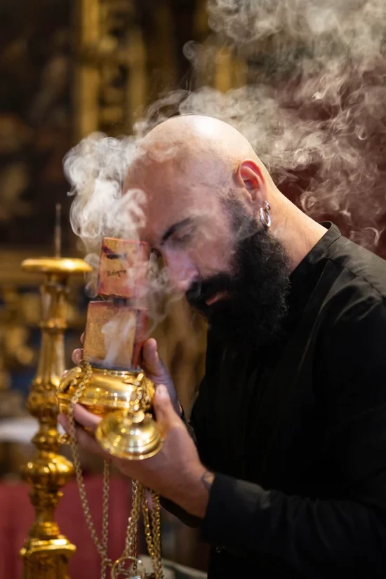 флакон парфуму біля різьбленого дерева й диму ладану