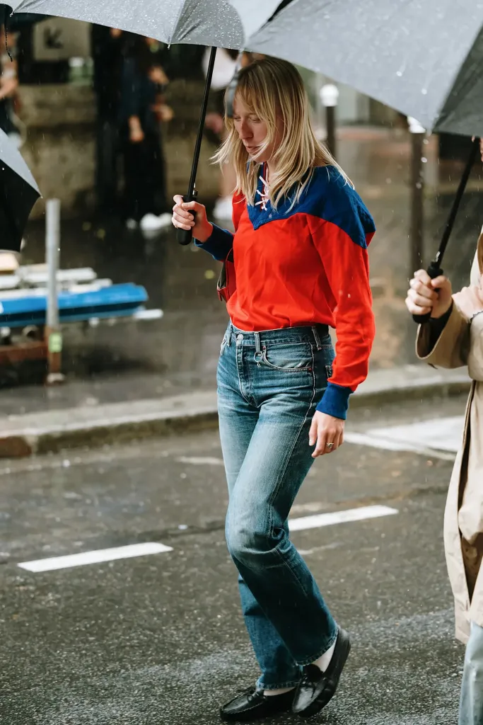 Деталь урбан-сцени: брюки slim fit на лавці, поруч лофери, куртка-бомбер, волога бруківка