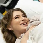 символічна сцена в палаті з люлькою, складеною дитячою ковдрою й долонями поруч, м’яке світло